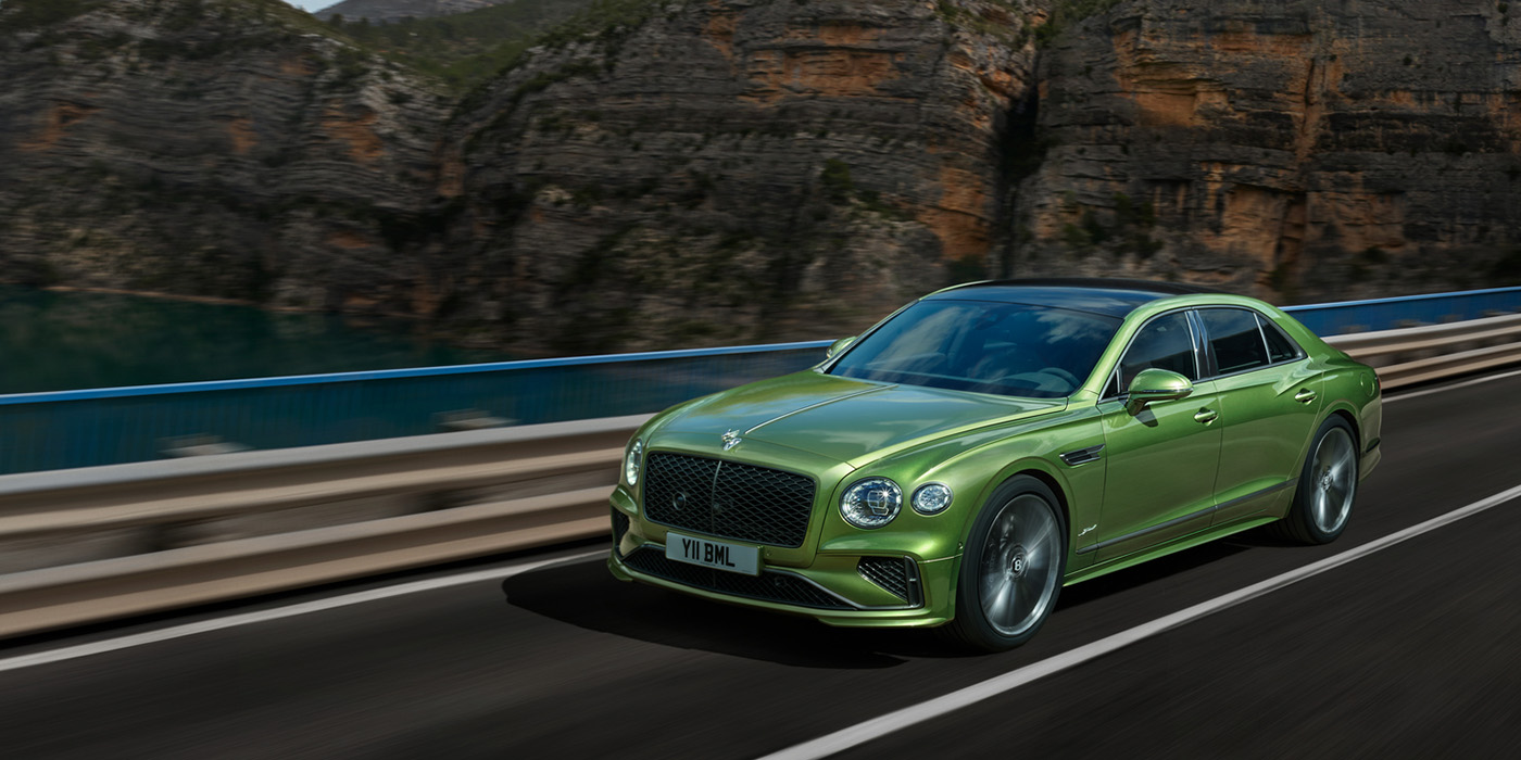 Bentley Maastricht Bentley New Flying Spur Speed v8 hybrid sedan driving dynamically on a mountain road in Tourmaline Green paint