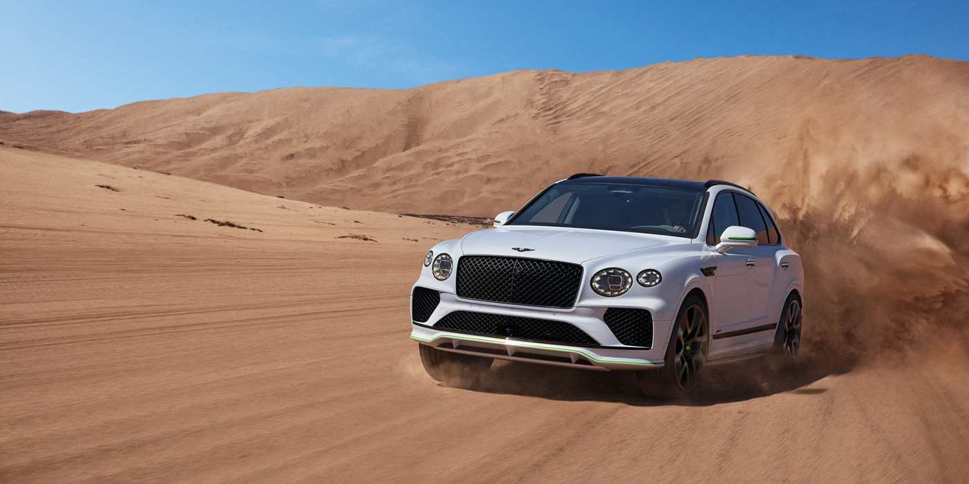 Bentley Maastricht Bentley Bentayga Speed SUV front three quarter in Snow Quarts Pearlescent by Mulliner white paint driving dynamically through the desert