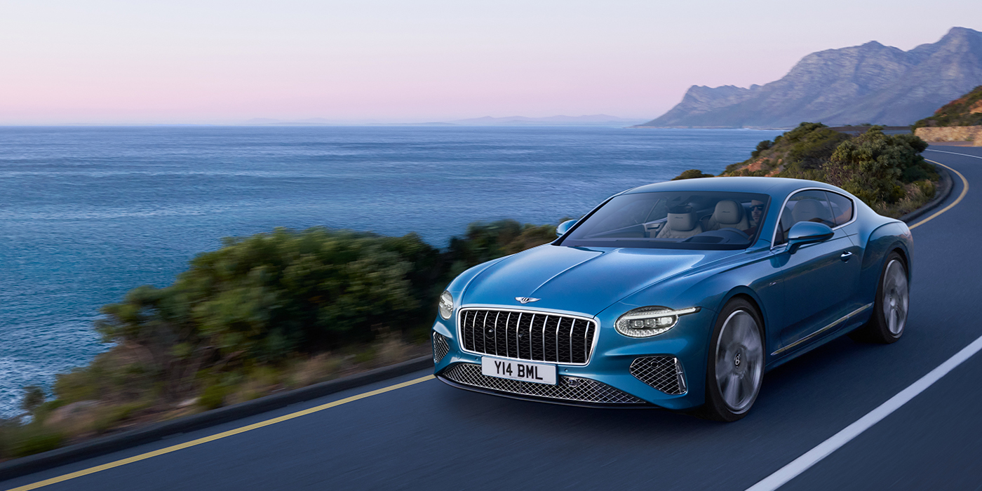 Bentley Maastricht New Bentley Continental GT Azure coupe in Light Windsor blue paint with 22 inch Azure wheels and chrome grill, driving dynamically by the sea