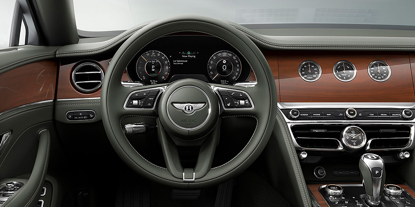 Bentley Maastricht New Bentley Flying Spur sedan front cabin in Cumbrian Green hide and Crown Cut walnut veneer showing steering wheel and Rotating Display with three clocks on face