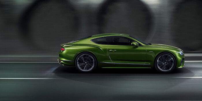  Bentley Maastricht Bentley Continental GT coupe in Tourmaline Green paint driving in profile on a dark road