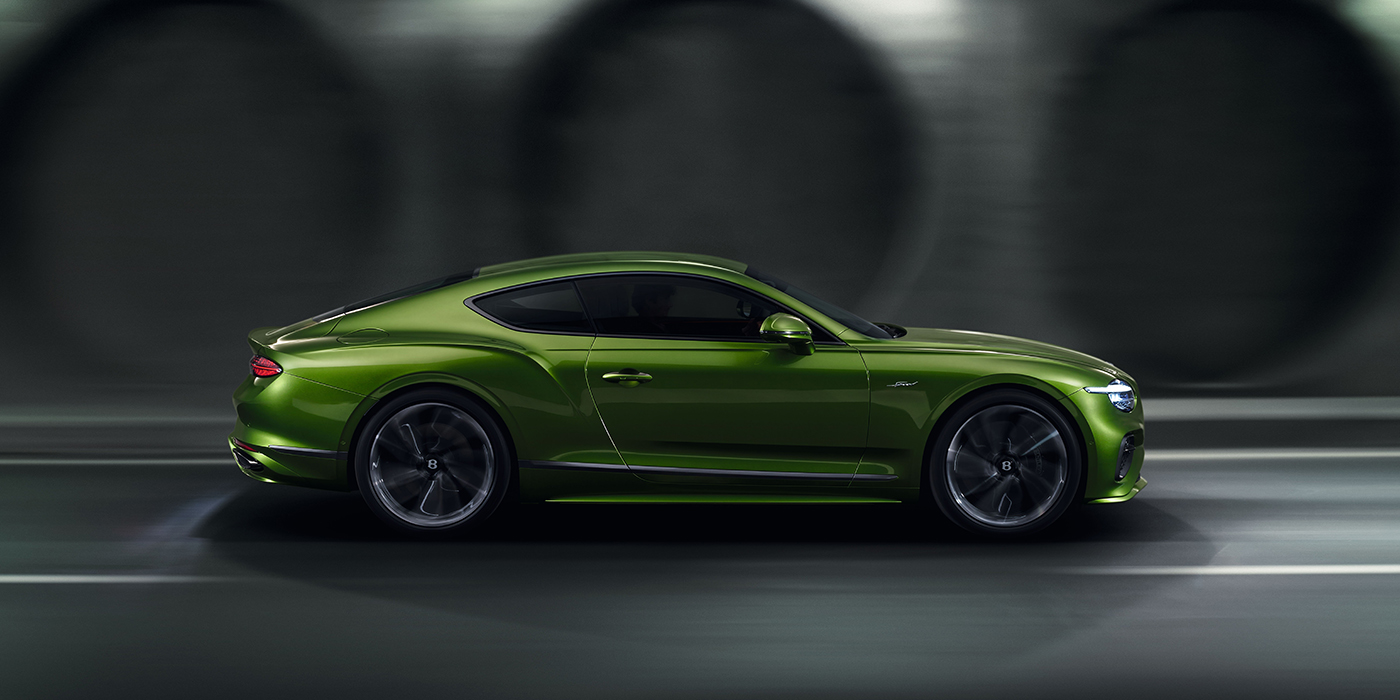 Bentley Maastricht Bentley Continental GT coupe in Tourmaline Green paint driving in profile on a dark road