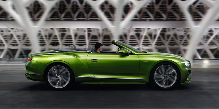 Bentley Maastricht Bentley Continental GTC Speed convertible side profile in Tourmaline Green paint driving dynamically on a bridge at night