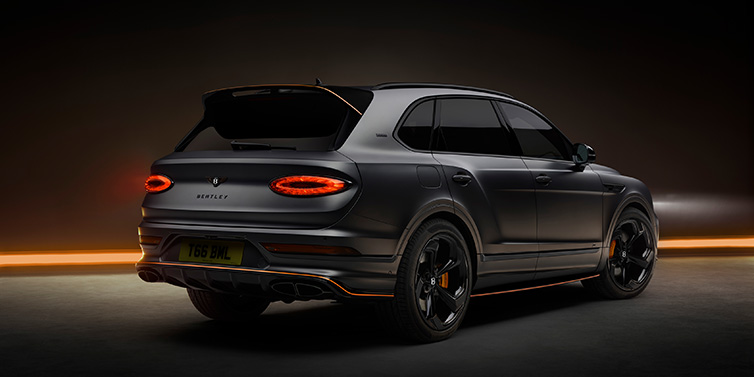 Bentley Maastricht Bentley Bentayga S Black Edition SUV rear three quarter in Anthracite Satin paint against a dark red and yellow background