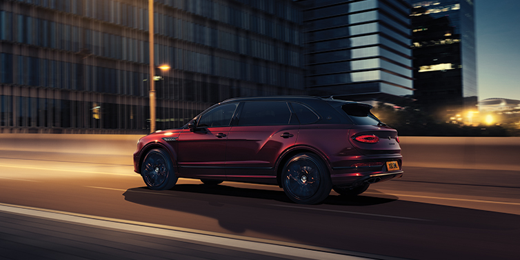Bentley Maastricht Bentley Bentayga Extended Wheelbase Mulliner SUV in Cricket Ball red paint driving dynamically in city at night