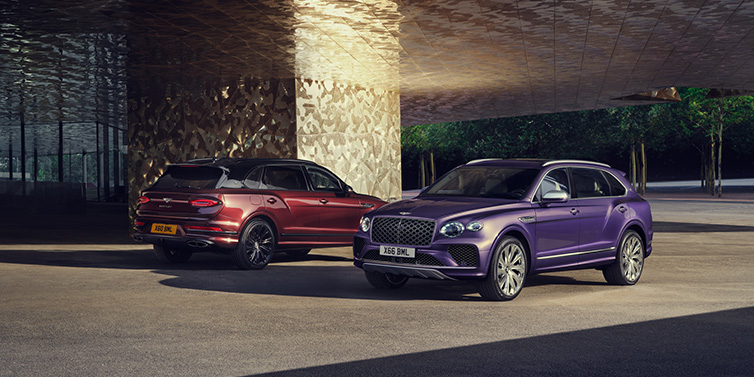 Bentley Maastricht A duo of Bentley Bentayga Extended Wheelbase Mulliner SUVs parked in a city environment, with Tanzanite Purple and Cricket Ball red exterior paint