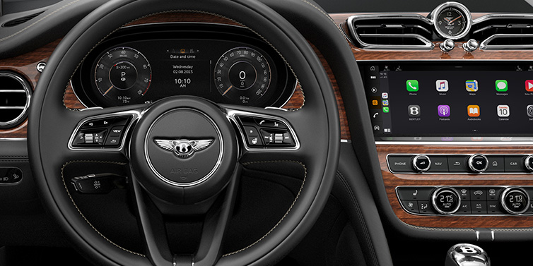 Bentley Maastricht Bentley Bentayga SUV front interior detail of steering wheel and driver screens surrounded by Beluga black hide and Crown Cut Walnut veneer